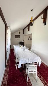 a long dining room with a white table and chairs at Villa Odorica in Gura Humorului