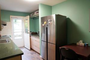 a kitchen with a stainless steel refrigerator and green walls at The Shearwater House - Panoramic Ocean View Suites in Nanaimo
