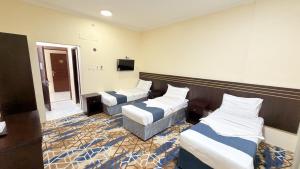 a hotel room with three beds and a tv at Sama Al Bayt in Mecca
