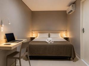 a bedroom with a bed and a desk with a laptop at Smart Hotel Aeroporto by Bsb Inn in Brasília