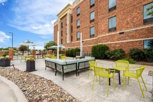 a patio with yellow chairs and tables and a building at Hampton Inn and Suites Swansboro Near Camp Lejeune in Swansboro