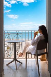 a woman sitting in a chair eating food on a balcony at Hotel Liberty Beach - Parking & Beach in Riccione