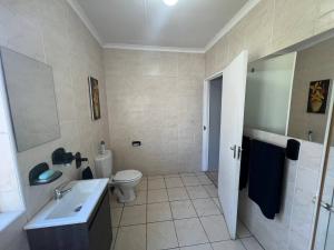 a white bathroom with a toilet and a sink at Stylish 1-Bed Cottage,Garden, Pool Secure Parking in Alberton +12 photos