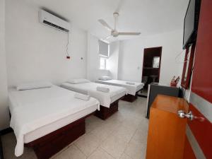 a room with three beds and a tv in it at Hotel MAR&ANA in El Banco