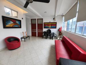 a waiting room with a red couch and chairs at Hotel MAR&ANA in El Banco