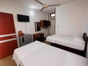 a hotel room with two beds and a flat screen tv at Hotel MAR&ANA in El Banco