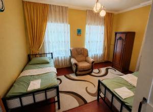 a bedroom with two beds and a chair in a room at GreenHouse in Qusar