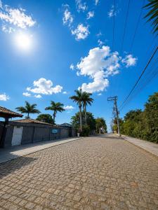 a cobblestone street with palm trees and a blue sky at Pousada Bella vista in Búzios +60 photos