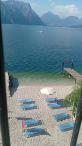 a group of beach chairs and an umbrella on a beach at Villa Monica in Malcesine +1 photo