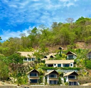a group of houses on a hill with trees at Bliss Resort in San Juan del Sur