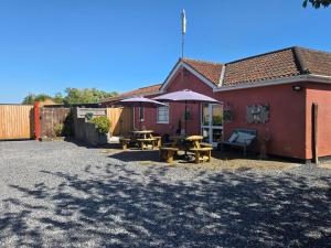 a red house with tables and umbrellas in front of it at Haybow Farm Accommodation in Rolstone