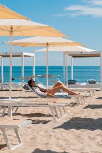 a woman laying in a chair on the beach at Hotel Liberty Beach - Parking & Beach in Riccione