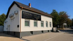 a white building with a sign on the side of it at Termál Vendégház in Leányfalu