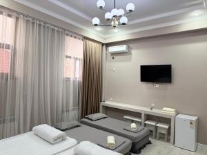 a hotel room with two beds and a flat screen tv at Nogai Karavan in Türkistan