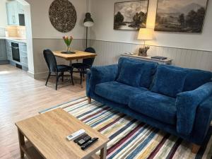 a living room with a blue couch and a table at Foxglove in Bicester +10 photos