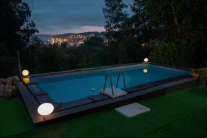 a swimming pool with lights in a backyard at night at O IGREXARIO Vacacional in Cangas de Morrazo