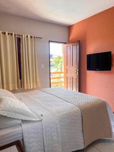 a bedroom with a large white bed with a flat screen tv at Pousada Missare in Canoa Quebrada