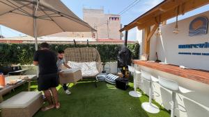 a man and a boy sitting in a chair under an umbrella at Marevita Hostel in Alicante