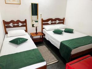two beds with green pillows in a room at Pousada Jara in Conservatória