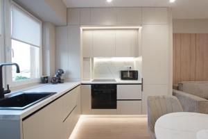 a kitchen with white cabinets and a sink and a table at Bacovia Grand Apartment- Free Parking in Bacău
