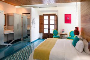 ein Schlafzimmer mit Bett, Waschbecken und Stühlen in der Unterkunft Del Carmen Concept Hotel Boutique by Chai in Guadalajara