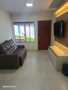 a living room with a couch and a flat screen tv at Casa de lagoa in Laguna