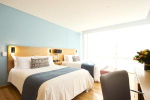 a hotel room with two beds and a window at Hotel bh Parque 93 in Bogotá