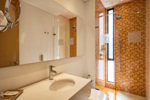 a bathroom with a sink and a mirror and a shower at Hotel bh Parque 93 in Bogotá