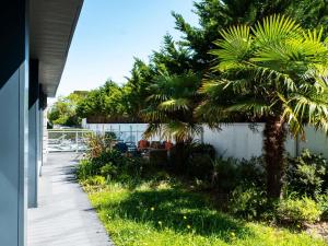 a backyard with palm trees and a fence at ibis Styles Quiberon Centre in Quiberon