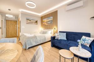 a living room with a bed and a blue couch at Wydmove Łeba Q4 Apartments in Łeba