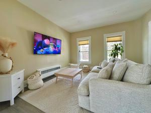 a living room with a couch and a tv on the wall at Clinton Rooms - By Outlets and Beach in Clinton