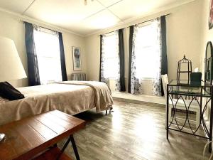 a bedroom with a bed and a table and windows at The Elizabeth Suite B2 in Hartford