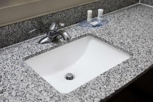 a white sink in a counter with a faucet at Humble Inn & Suites in Humble +20 photos