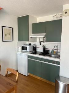 a kitchen with green cabinets and a microwave at Studio centre ville - 5min de la plage in Neufchâtel-Hardelot