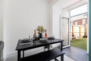 a dining room with a black table and a window at 3 Bedroom House In Jarrow, Sleeps 6, Near Port of Tyne & Free Parking in Jarrow