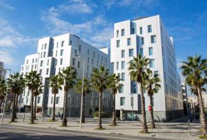 dos edificios blancos con palmeras frente a una calle en Durlet Beach Apartments, en Barcelona