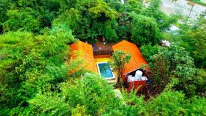 an orange house in the middle of trees at K Bhoomi Joy by Earth in Bhīra Camp
