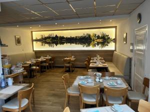 a restaurant with tables and chairs and a painting on the wall at Hotel Holländischer Hof in Lich