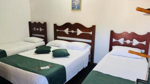 two beds in a room with green and white at Pousada Jara in Conservatória +4 photos