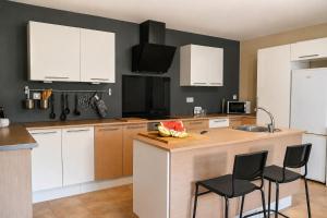 a kitchen with white cabinets and a counter with chairs at O IGREXARIO Vacacional in Cangas de Morrazo