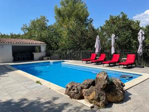 a swimming pool with red chairs and umbrellas at Appartement tout confort à Auriol in Auriol