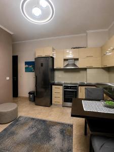 a kitchen with a stainless steel refrigerator and a table at SiMar Apartment Tirana in Kashari +2 photos