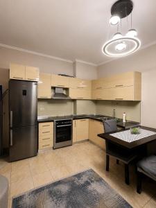 a kitchen with a stainless steel refrigerator and a table at SiMar Apartment Tirana in Kashari