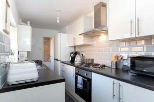 a kitchen with white cabinets and a black counter top at 3 Bedroom House In Jarrow, Sleeps 6, Near Port of Tyne & Free Parking in Jarrow