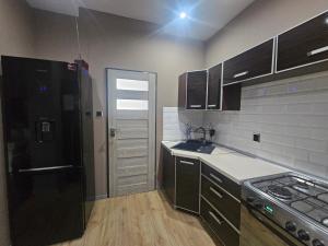 a kitchen with a black refrigerator and wooden floors at Apartament DARIS in Wałbrzych