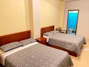 a bedroom with two beds and a window with an aquarium at Hostal acacias in Cuenca