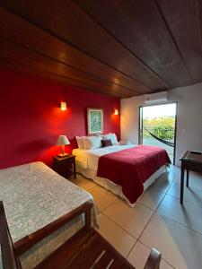 a bedroom with two beds and a red wall at Pousada Solar D Alcina in Paraty