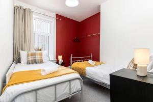 two beds in a room with red walls at 3 Bedroom House In Jarrow, Sleeps 6, Near Port of Tyne & Free Parking in Jarrow