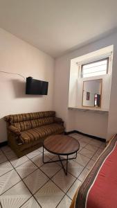 a living room with a couch and a television at Hotel Dulce Morelia in Morelia