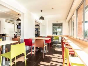 a restaurant with colorful chairs and tables at ibis budget Bourges in Bourges